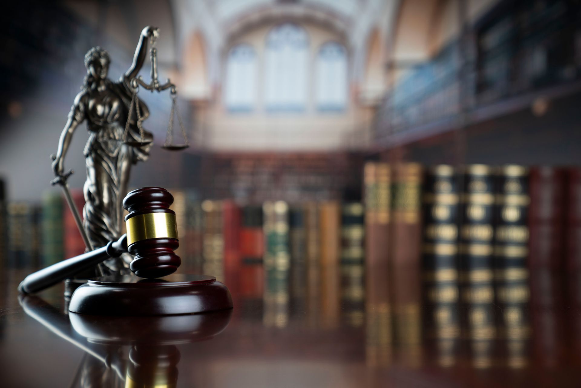 A gavel is sitting on a table in a library next to a statue.