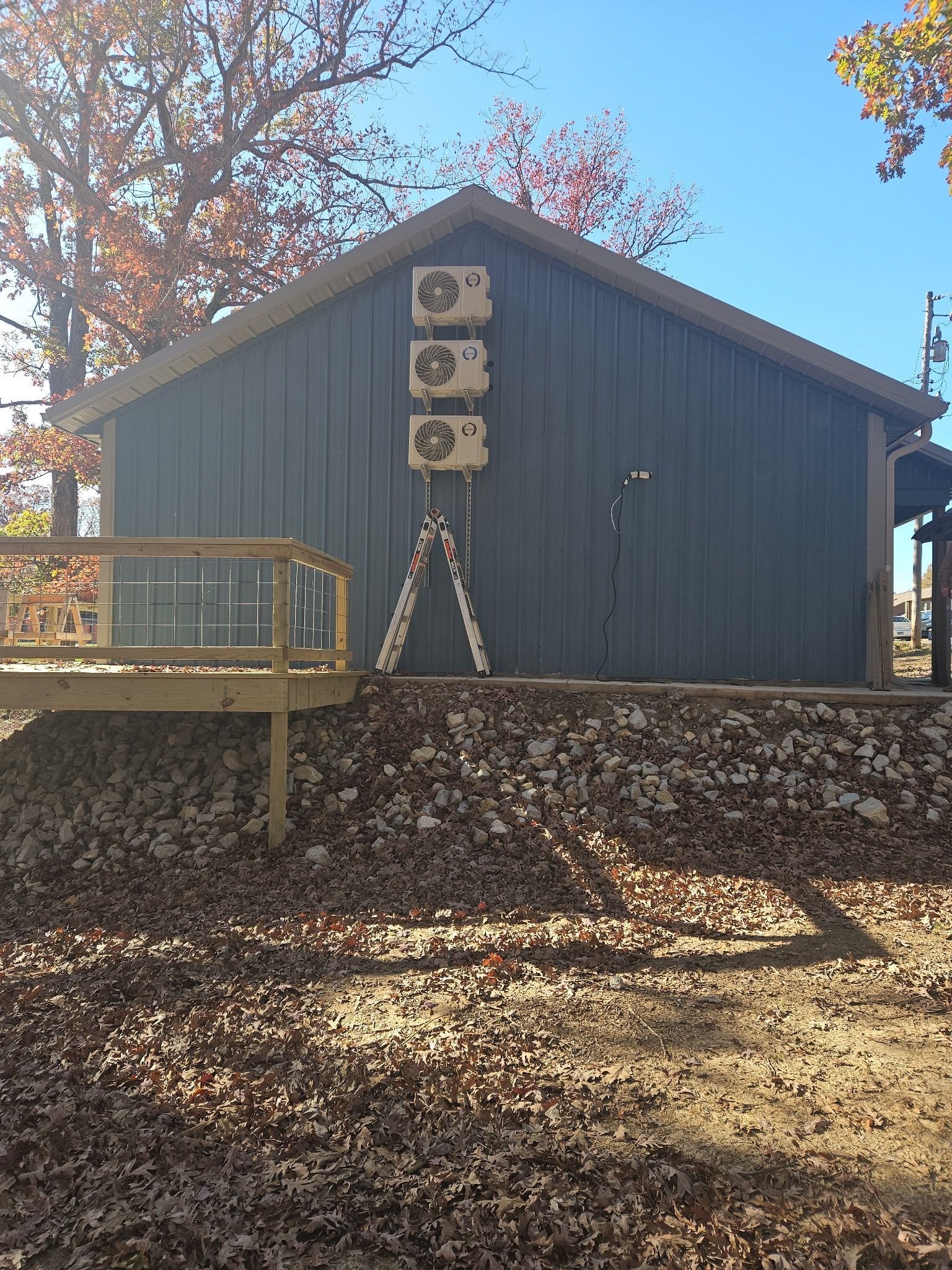A ladder is sitting on the side of a building next to a deck.