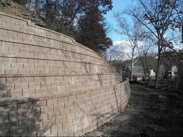 A large brick wall is surrounded by trees on a hillside.