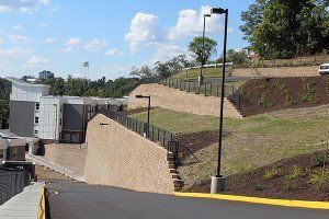 A fence surrounds a hill with a building in the background.