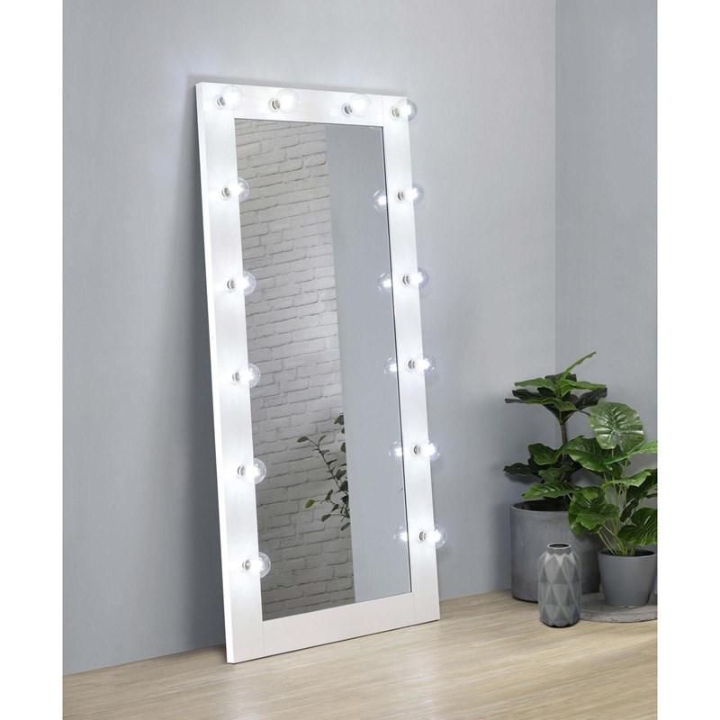 A full length mirror with lights on it is sitting on a wooden floor in a room.
