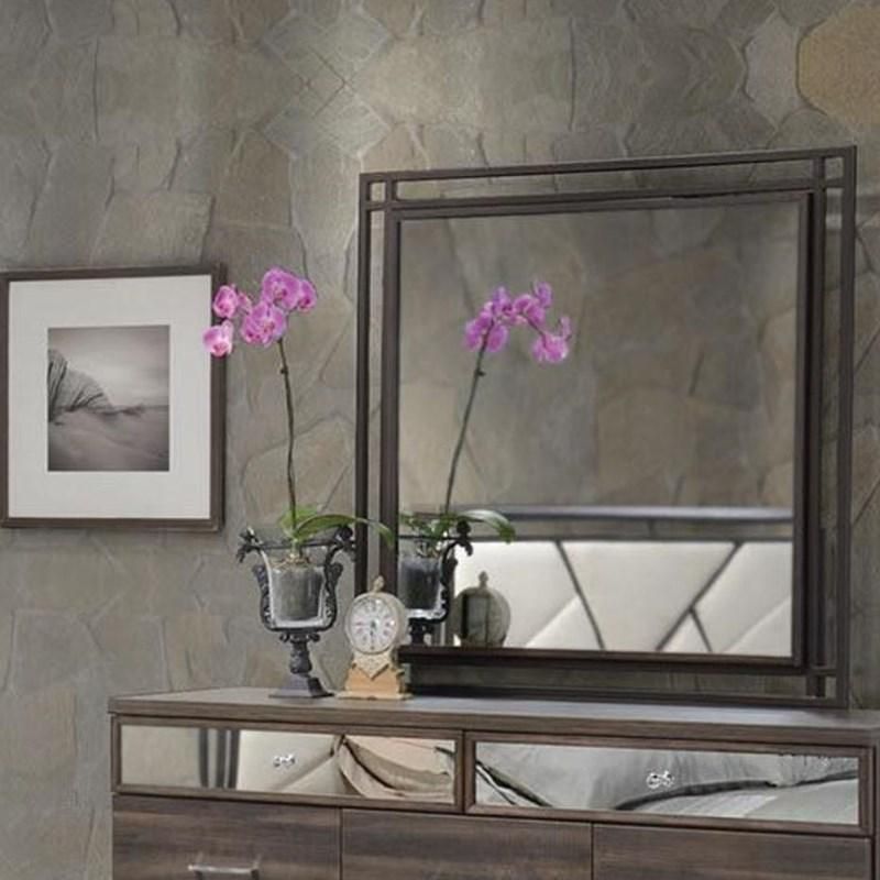 A bedroom with a dresser a mirror and a picture on the wall