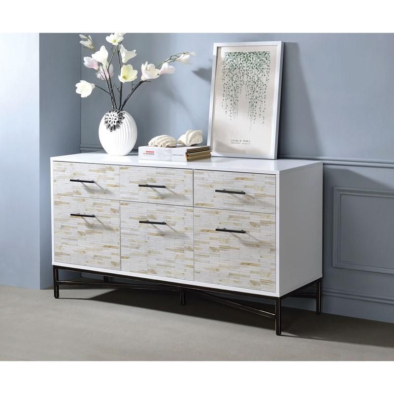 A white dresser with a vase of flowers on top of it