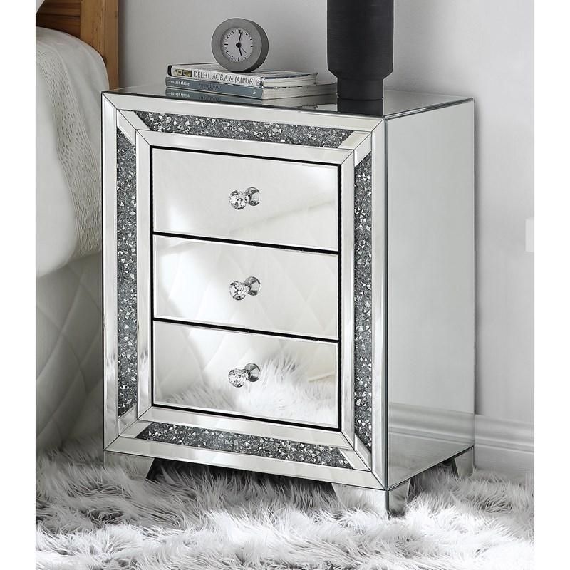 A mirrored nightstand with three drawers and a clock on top of it.