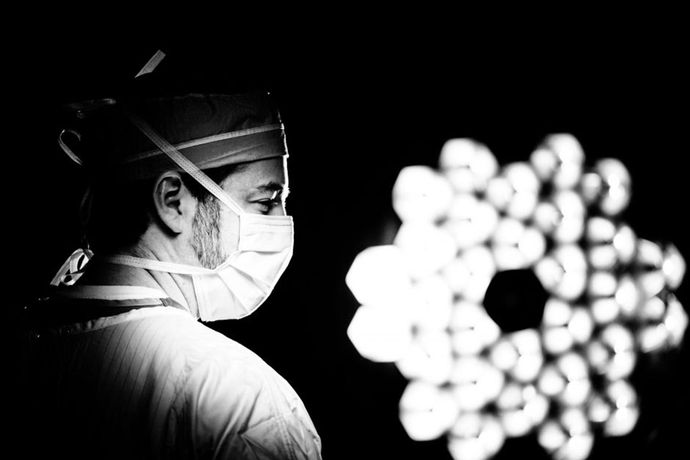 A black and white photo of a surgeon in an operating room.