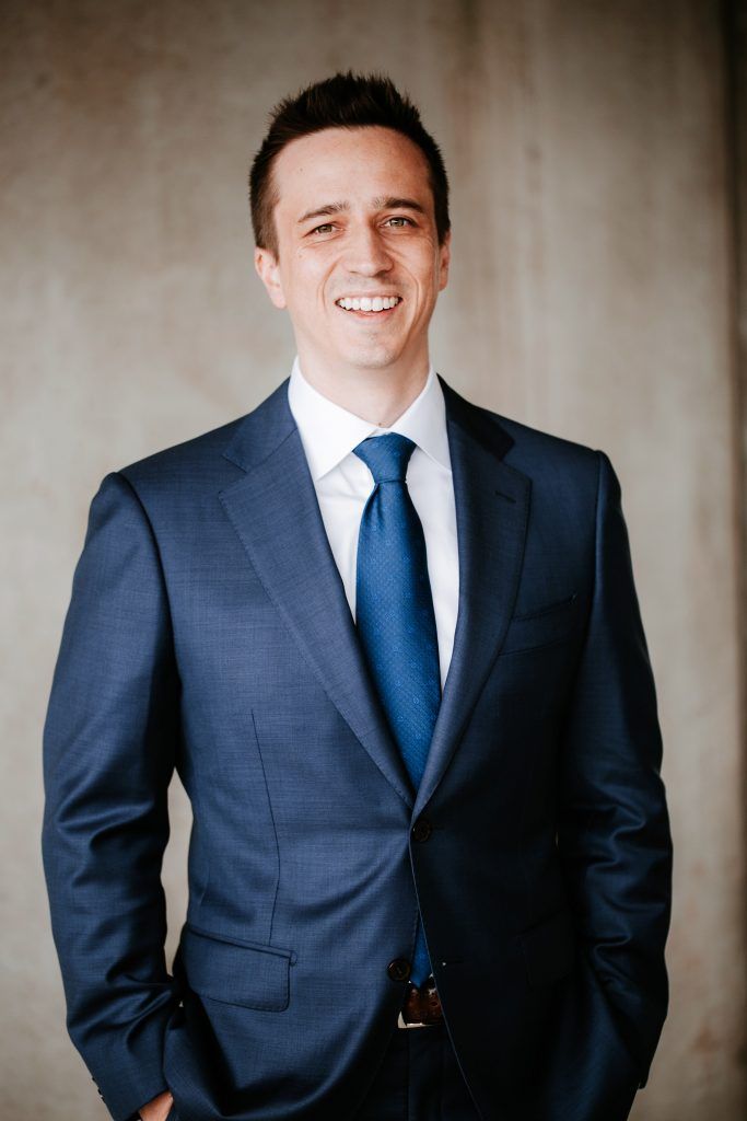 A man in a suit and tie is standing with his hands in his pockets.