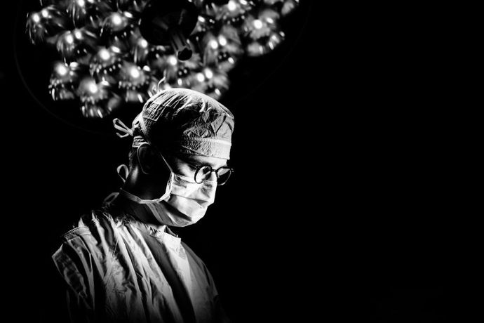 A black and white photo of a surgeon in an operating room.