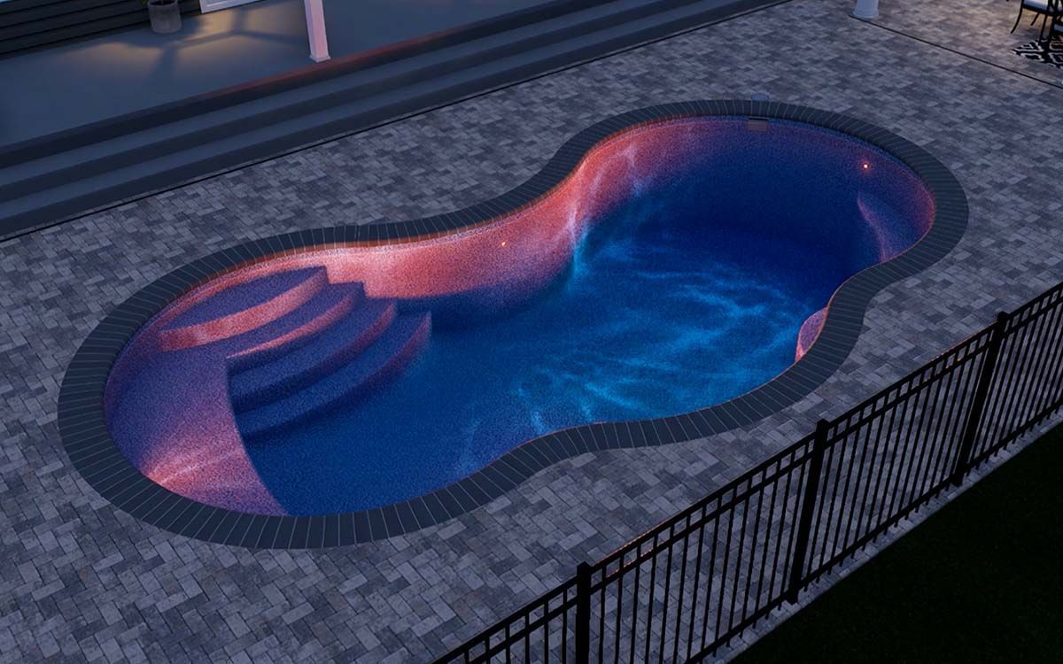 Night view of a glowing pool with steps, surrounded by brick paving and a black fence.