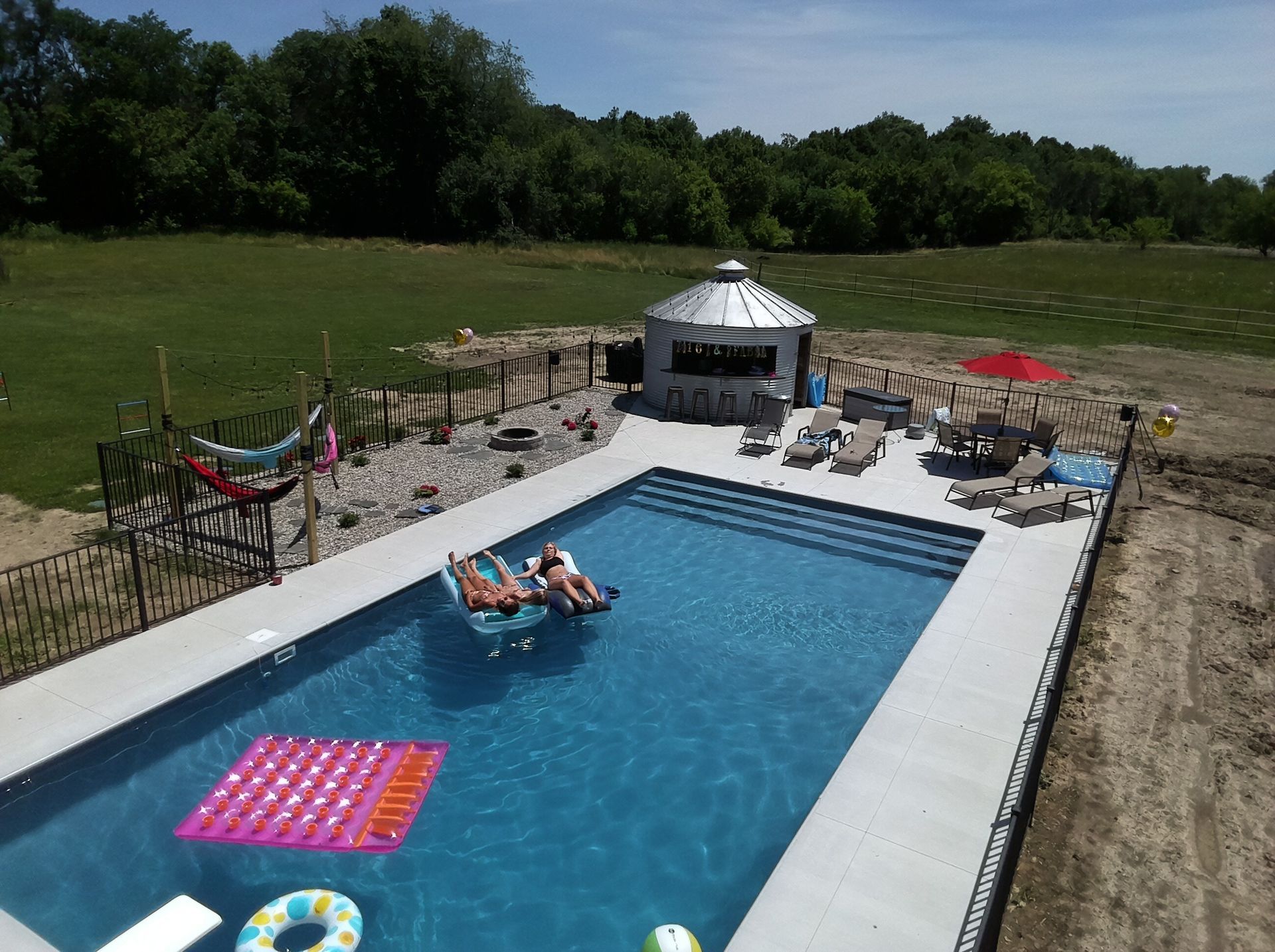 An aerial view of a large swimming pool with a gazebo in the background.