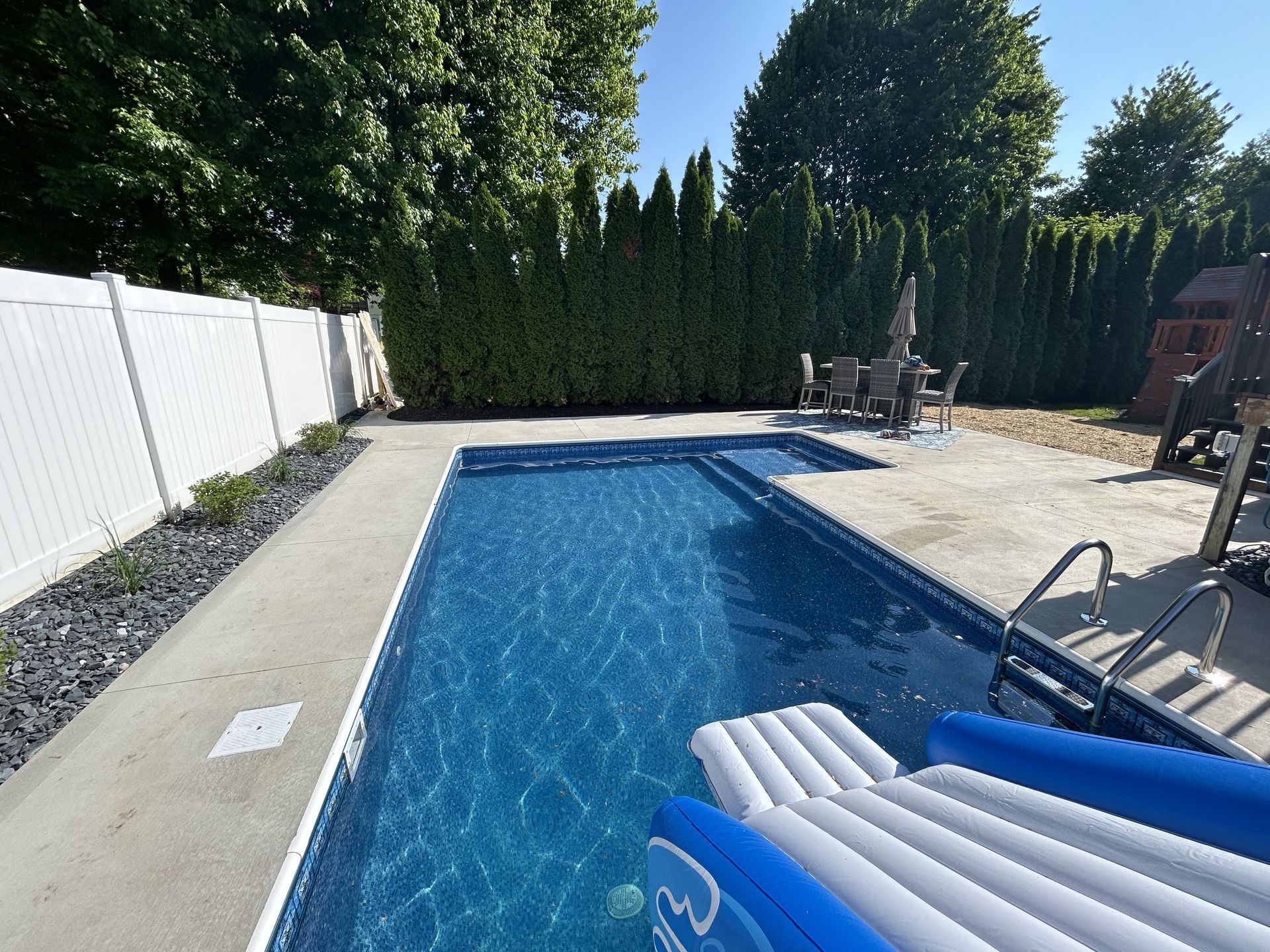 A large swimming pool with a white fence surrounding it
