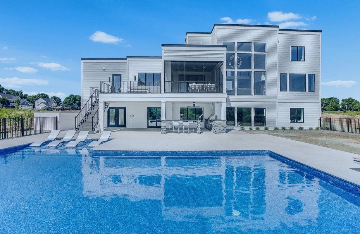 A large white house with a large swimming pool in front of it.