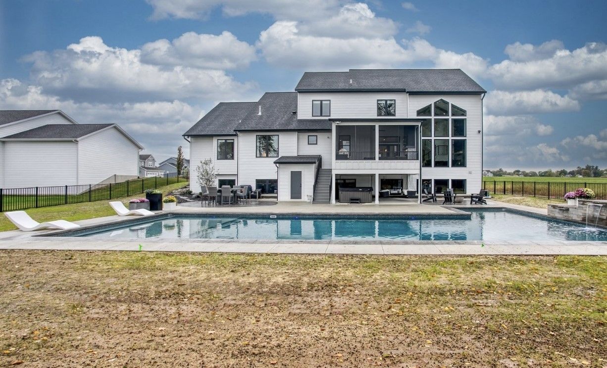 A large white house with a large swimming pool in the backyard.