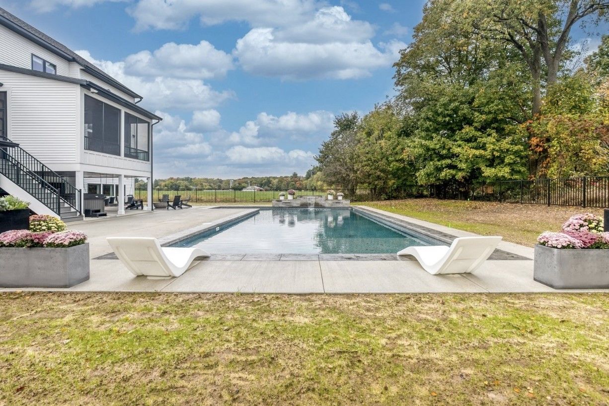 There is a large swimming pool in the backyard of a house.