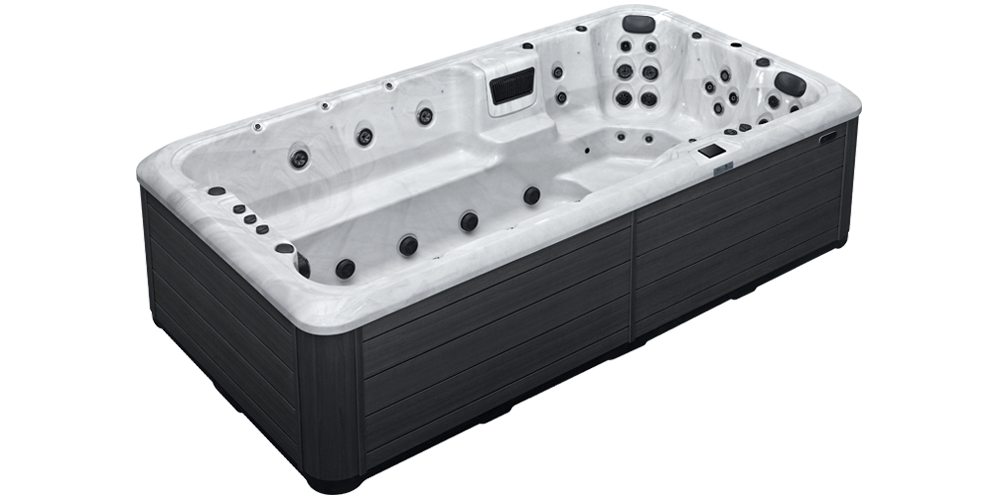 An outdoor swim spa with a dark gray exterior, white interior, and multiple massage jets.