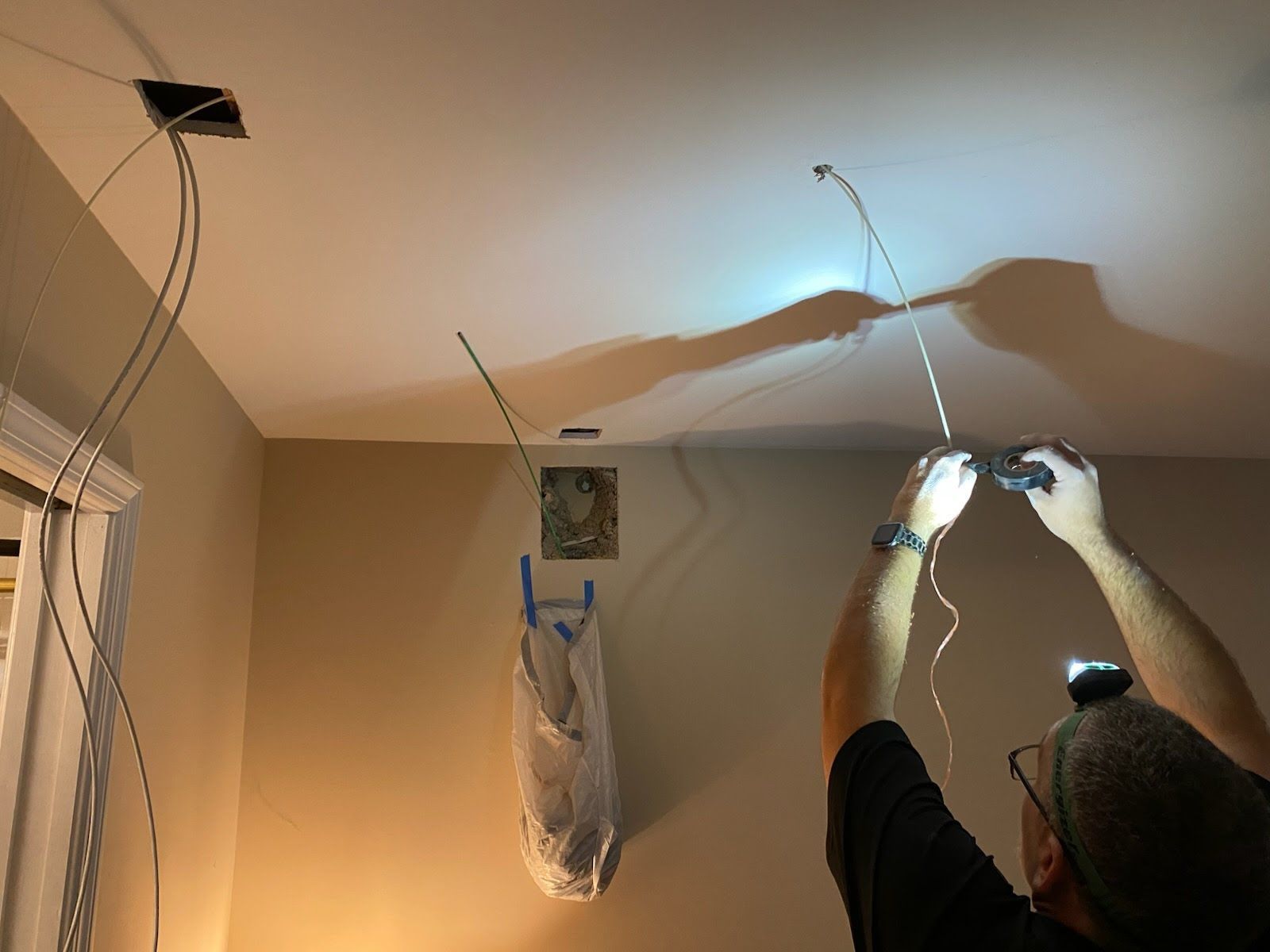 A man is working on a ceiling with a flashlight