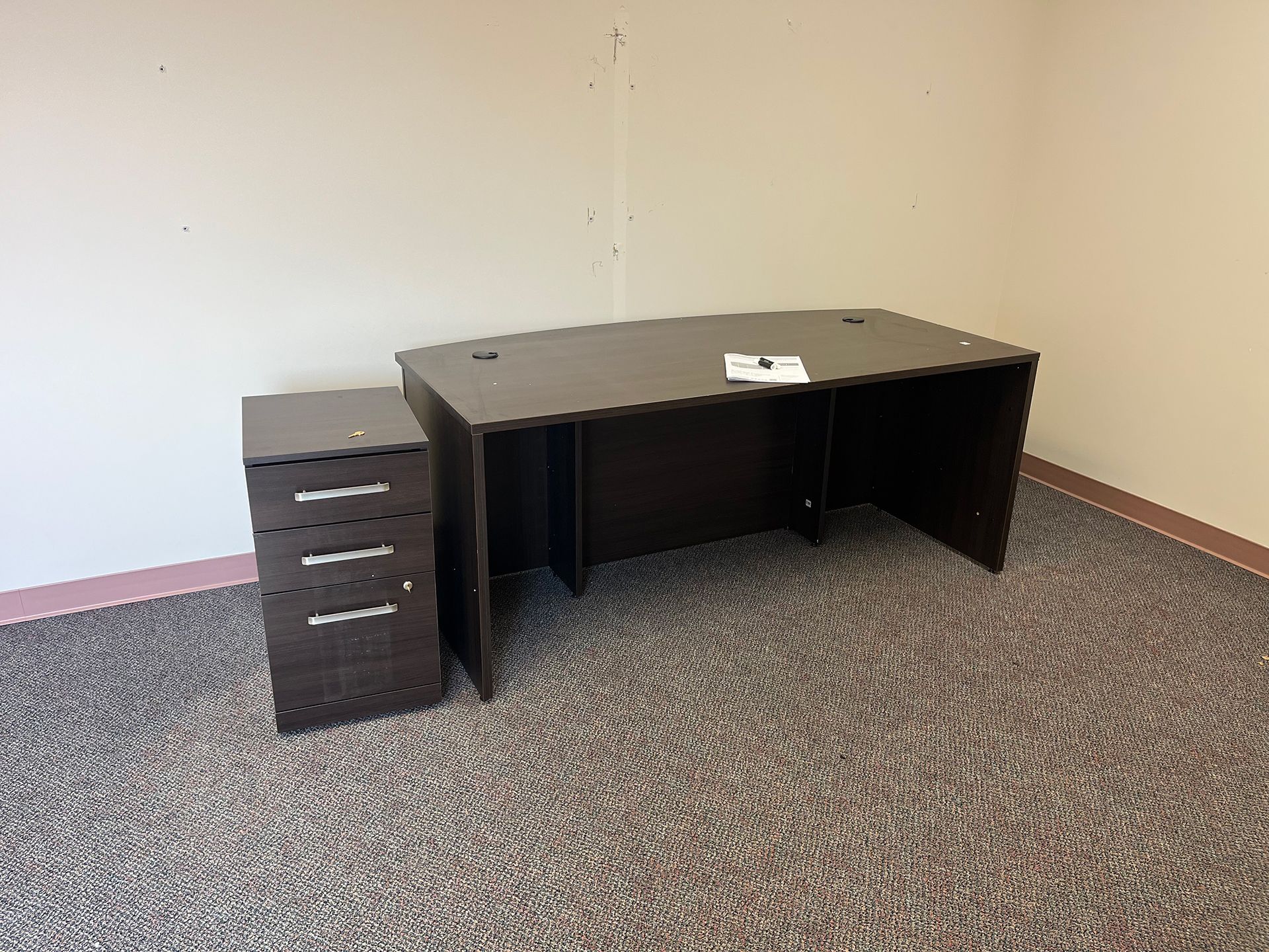 An empty office with a desk and a filing cabinet