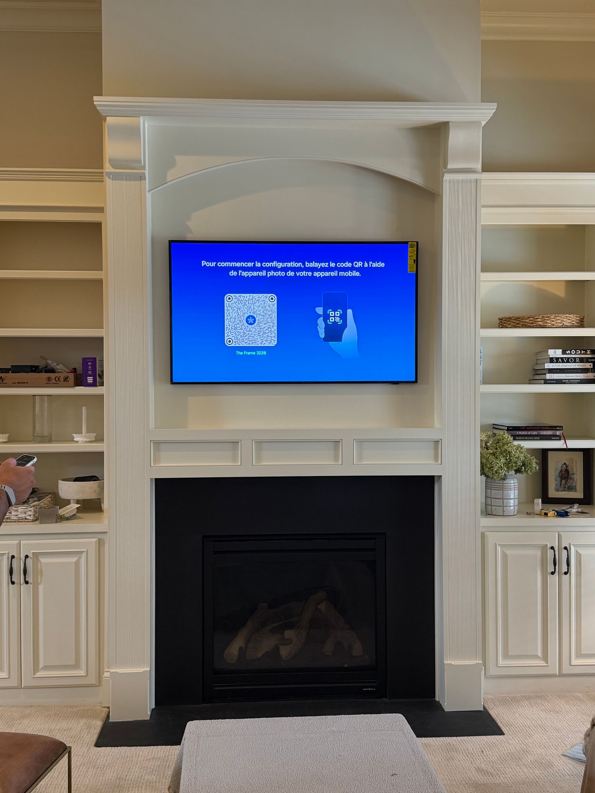 TV screen above a fireplace, set in a white built-in cabinet. Blue screen with setup prompts. 