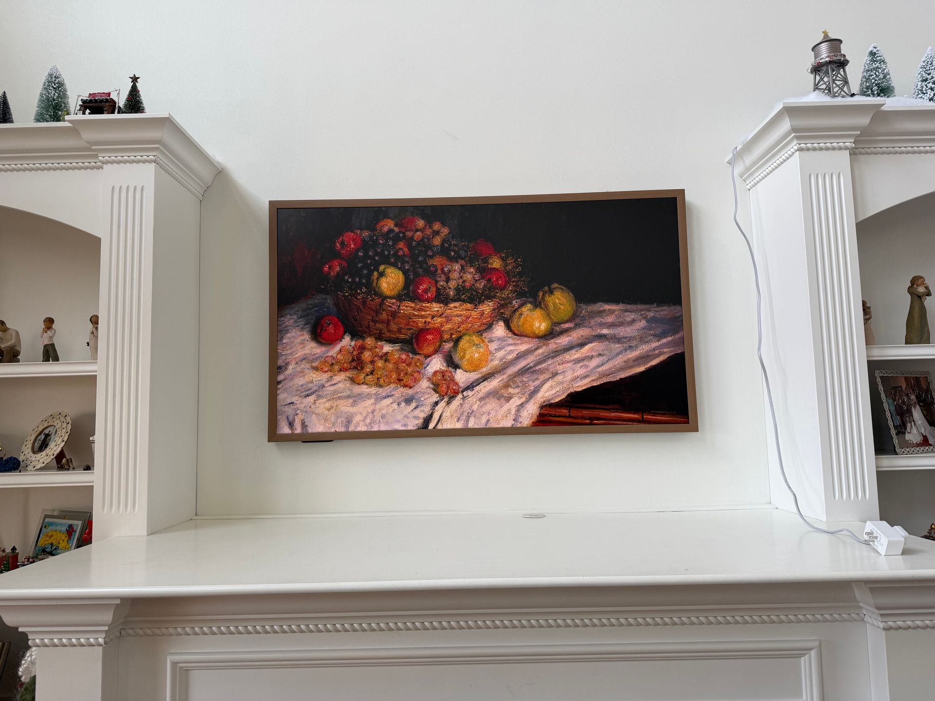 Painting of fruit basket and pears displayed above a fireplace mantel, flanked by built-in shelving. 
