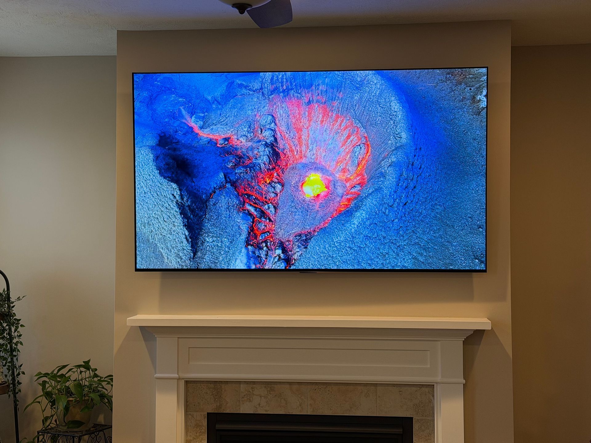 Large TV displaying colorful abstract art mounted above a fireplace. 