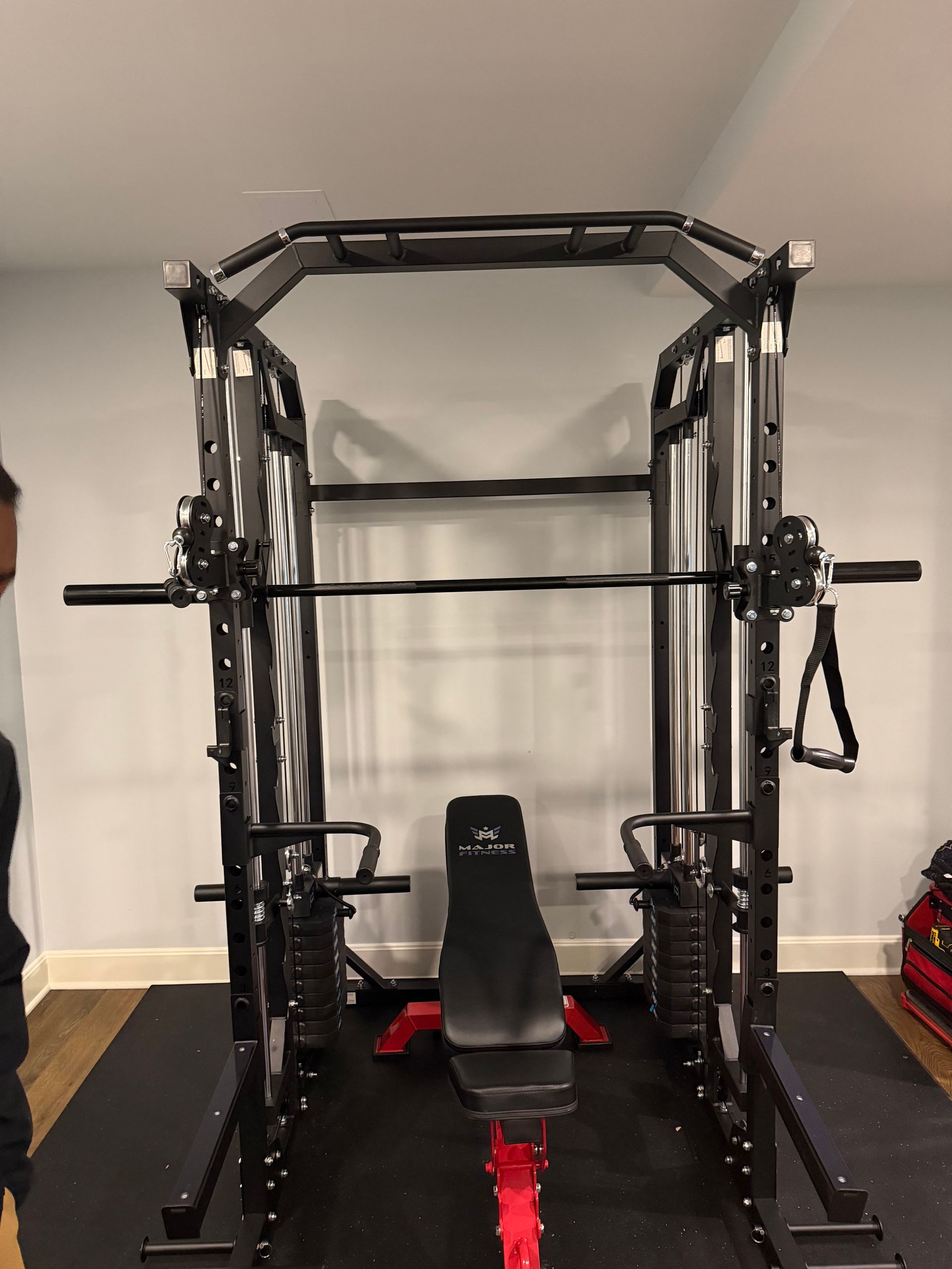 Black multi-gym with weight bench and weight stacks in a home gym. 