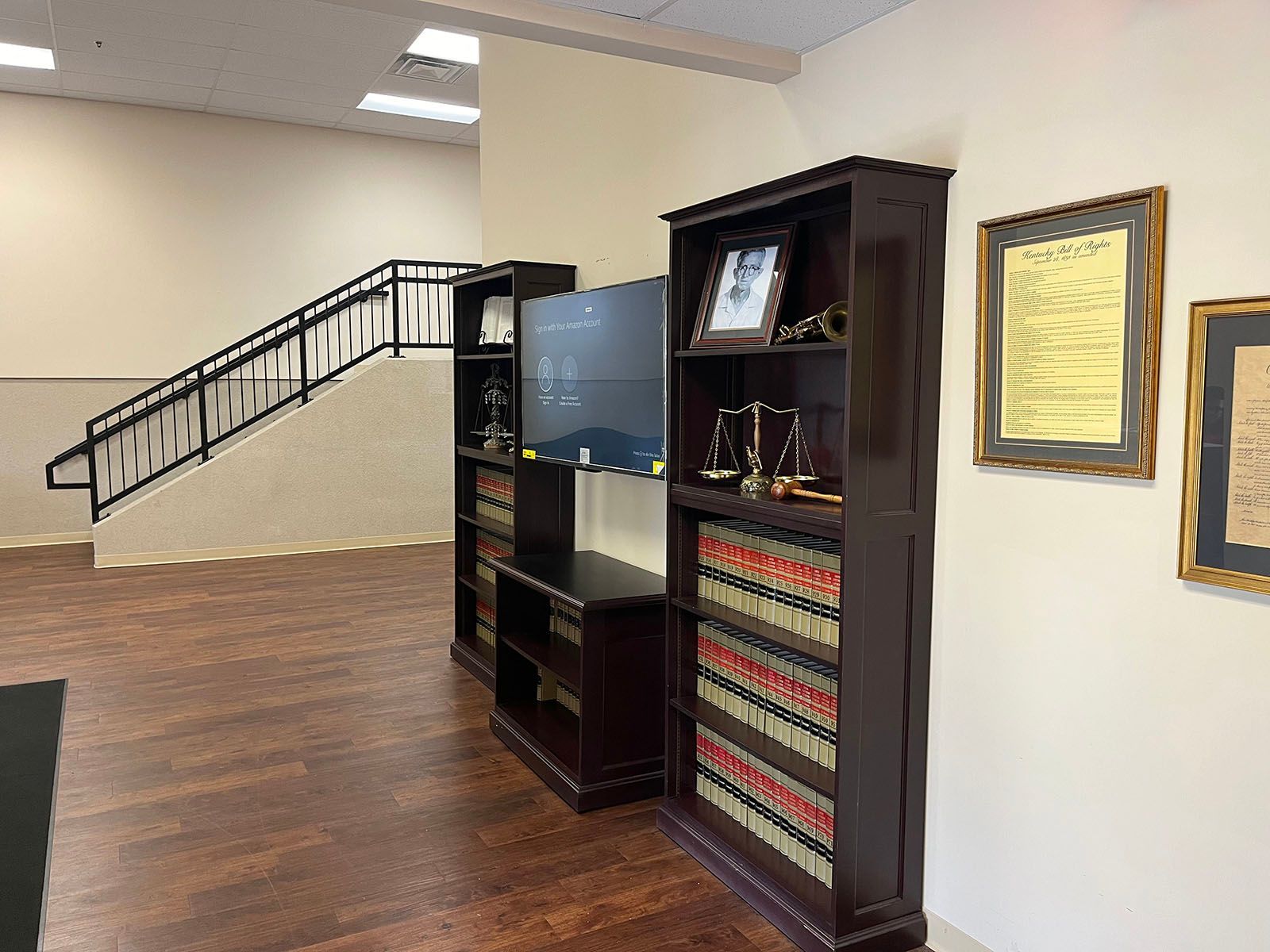 A living room with a staircase and a tv on a shelf