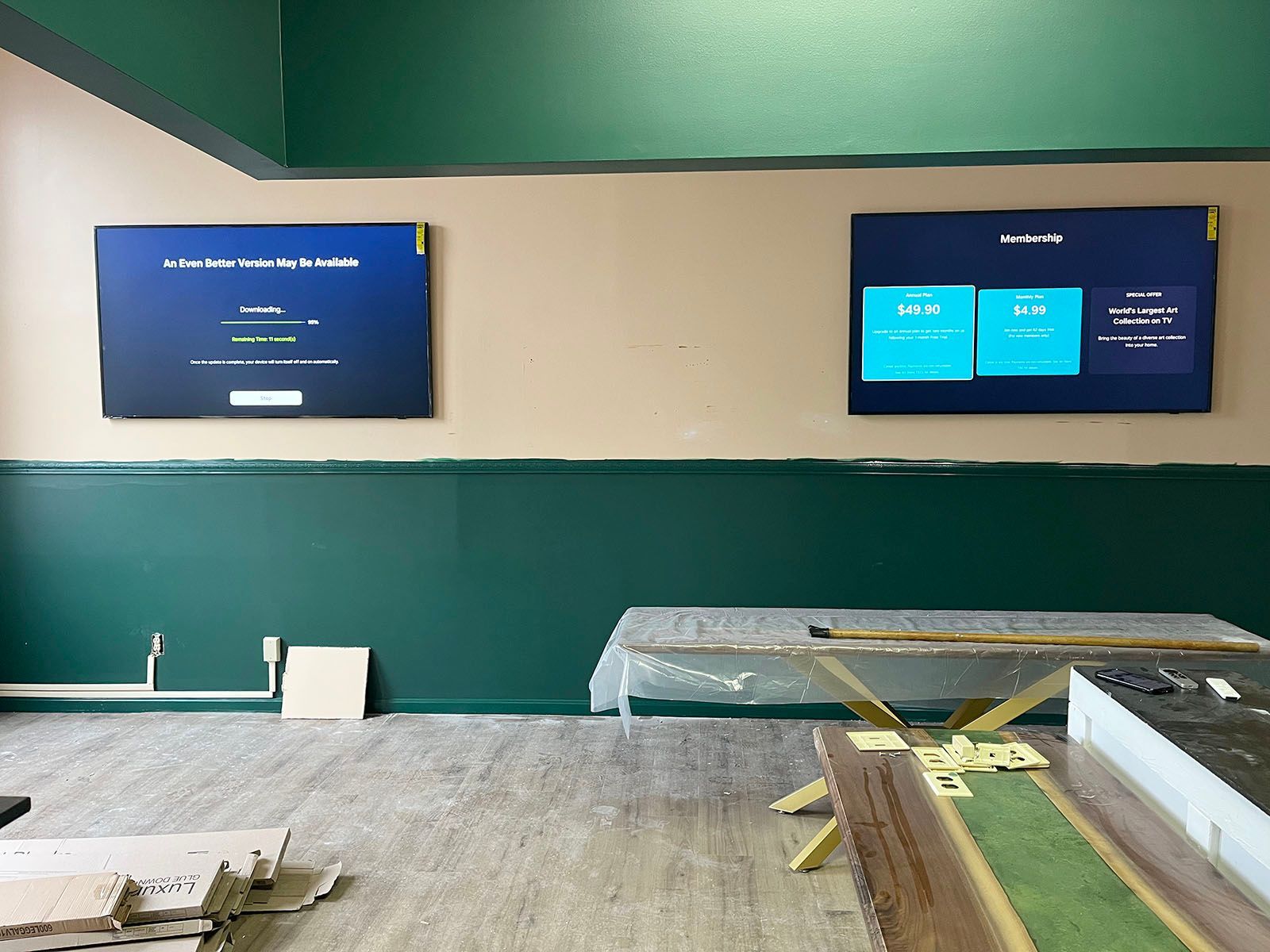 A room with green walls and two televisions on the wall