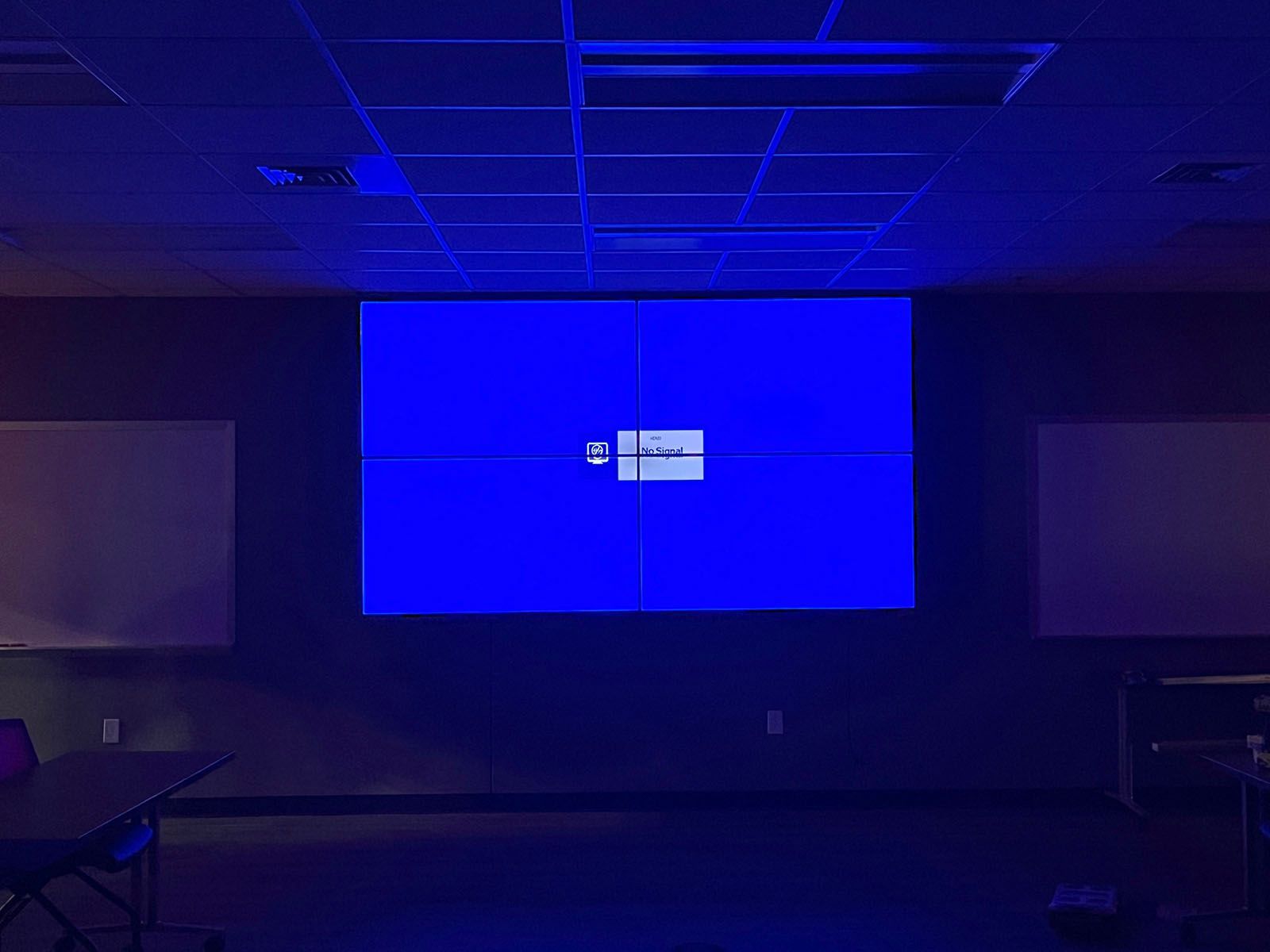 A large blue screen is hanging from the ceiling in a dark room