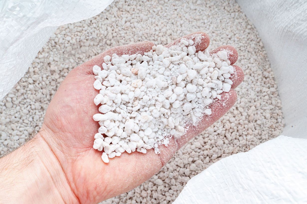 Hand holding white pebbles over a bed of small gray stones