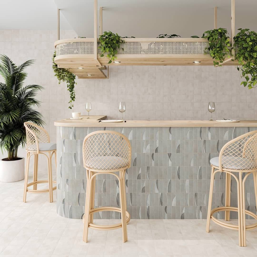 A kitchen with a bar and stools and a plant.
