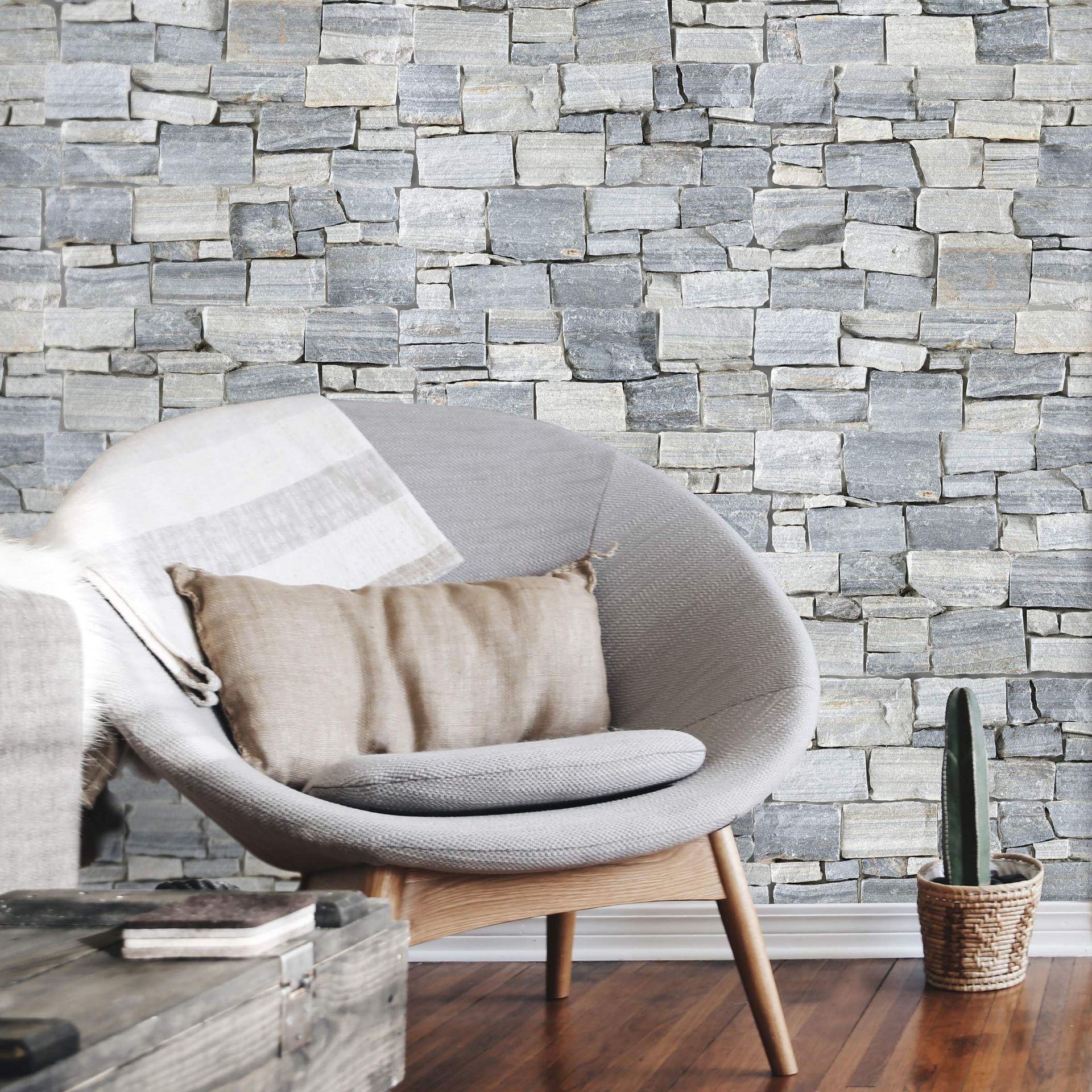 A chair with a pillow on it in front of a stone wall.