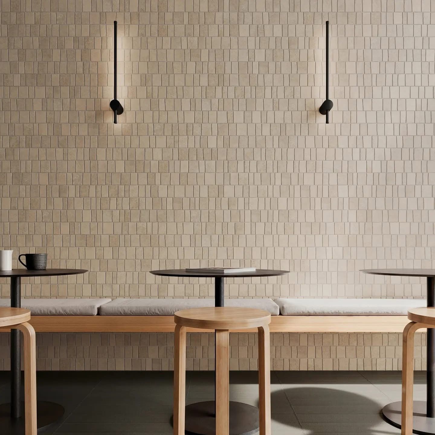 A row of tables and stools in front of a brick wall.