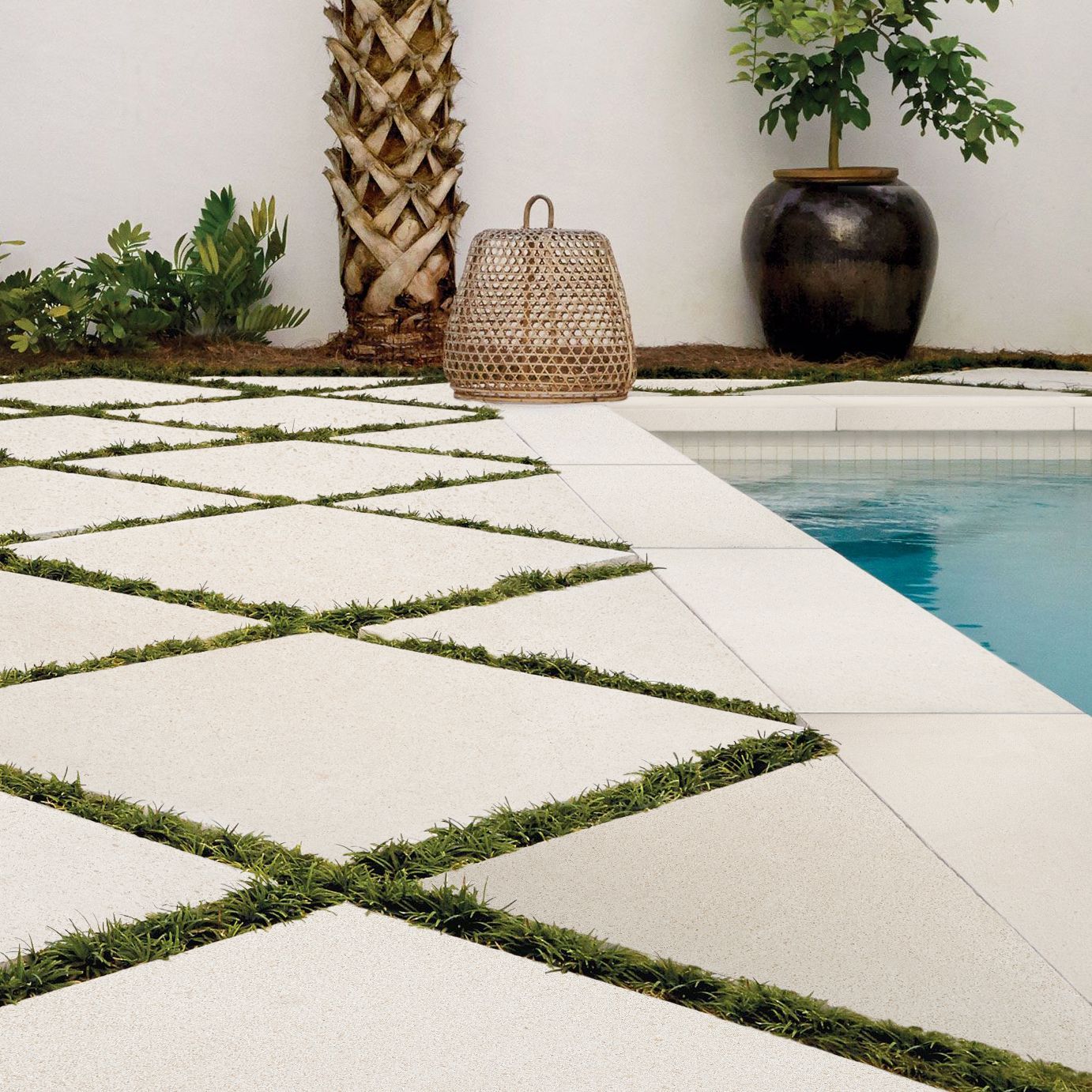 A wicker basket sits on a patio next to a swimming pool