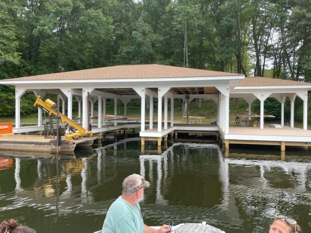 A man is sitting on a boat in front of a dock.