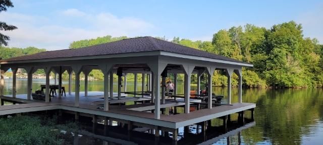 A gazebo is sitting on top of a dock in the middle of a lake.