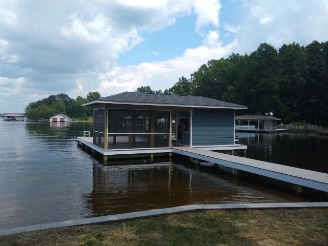 A house is sitting on a dock in the middle of a lake.