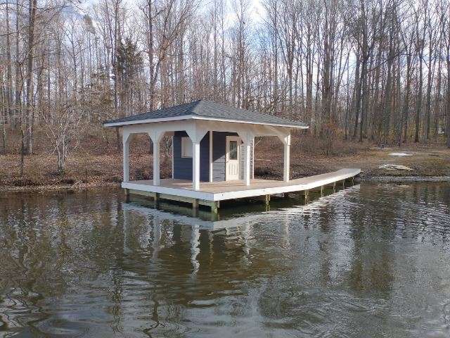 A small house is sitting on a dock in the middle of a lake.