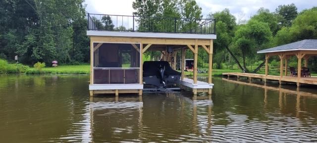 A boat is sitting under a dock in the middle of a lake.