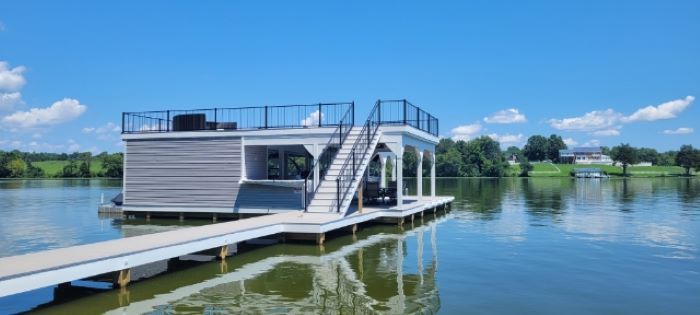 A floating house is sitting on top of a dock in the middle of a lake.