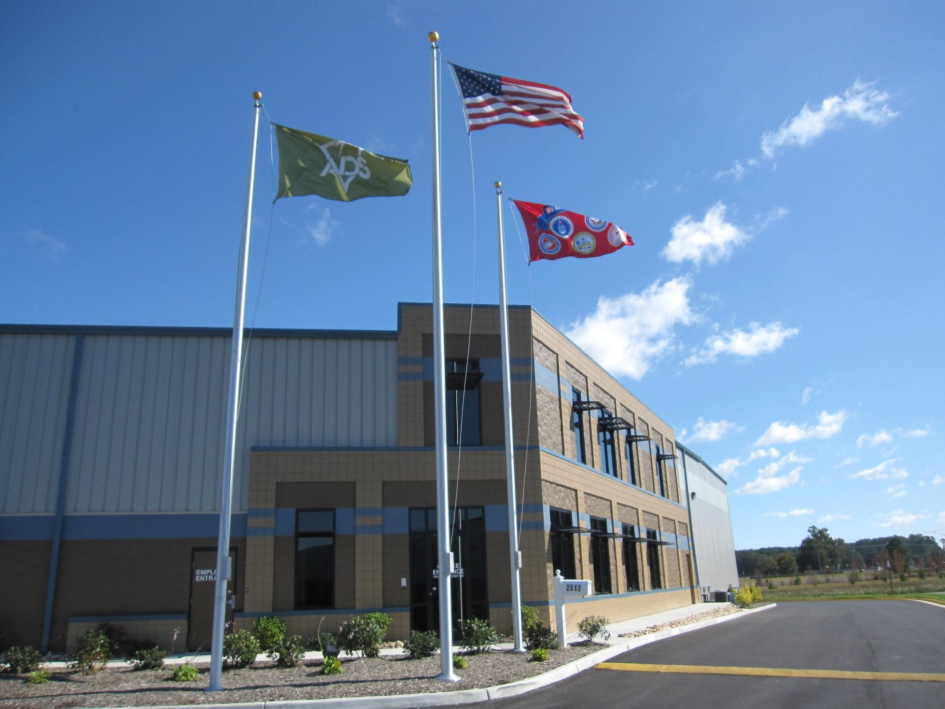 Three flags are flying in front of a building