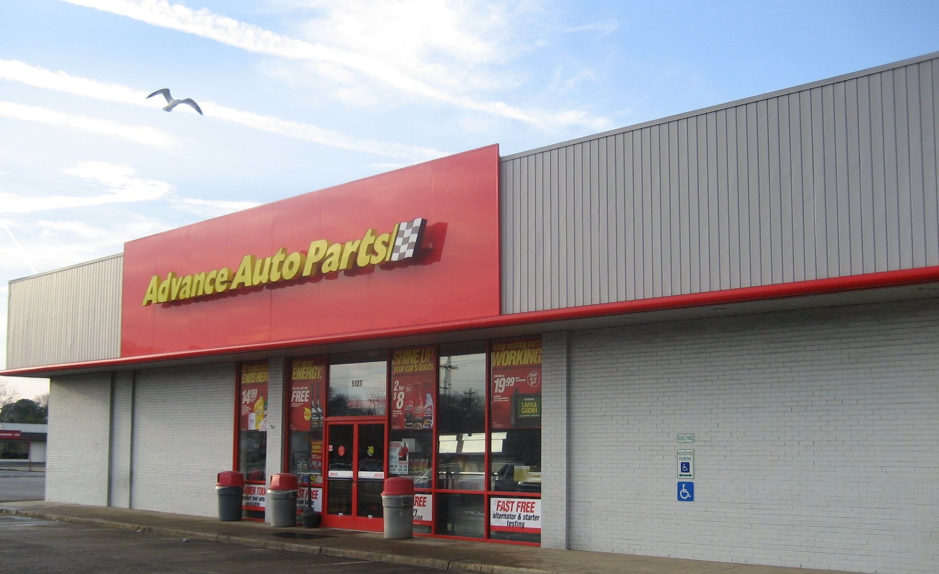A white building with a red sign that says advance auto parts