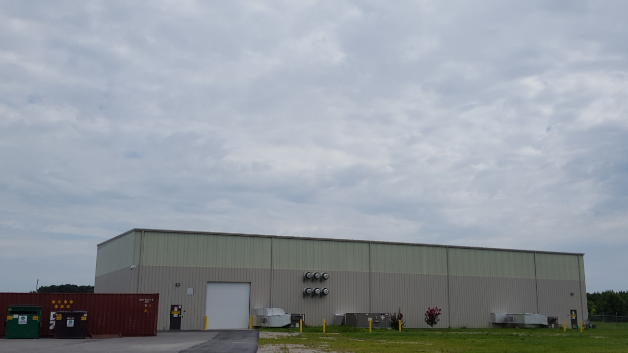 A large building with a white door is sitting in the middle of a field.