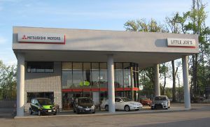 A mitsubishi motors dealership with cars parked in front of it.