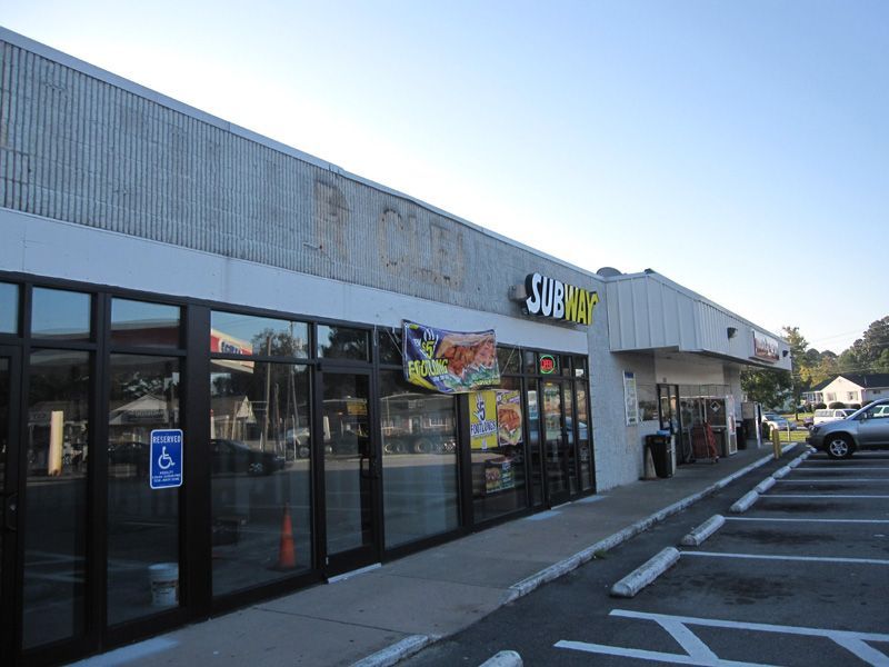 A subway restaurant is located in a parking lot.