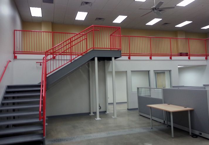 An empty office with a red railing and stairs