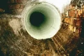Close-up of a white circular pipe opening against a rusty, brown metal surface.