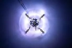 Glowing blue sci-fi device or drone centered in a dark purple background, with four extended arms