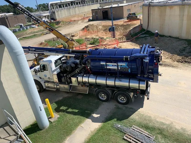 Blue drilling rig truck at a construction site with a crane and exposed ground soil area