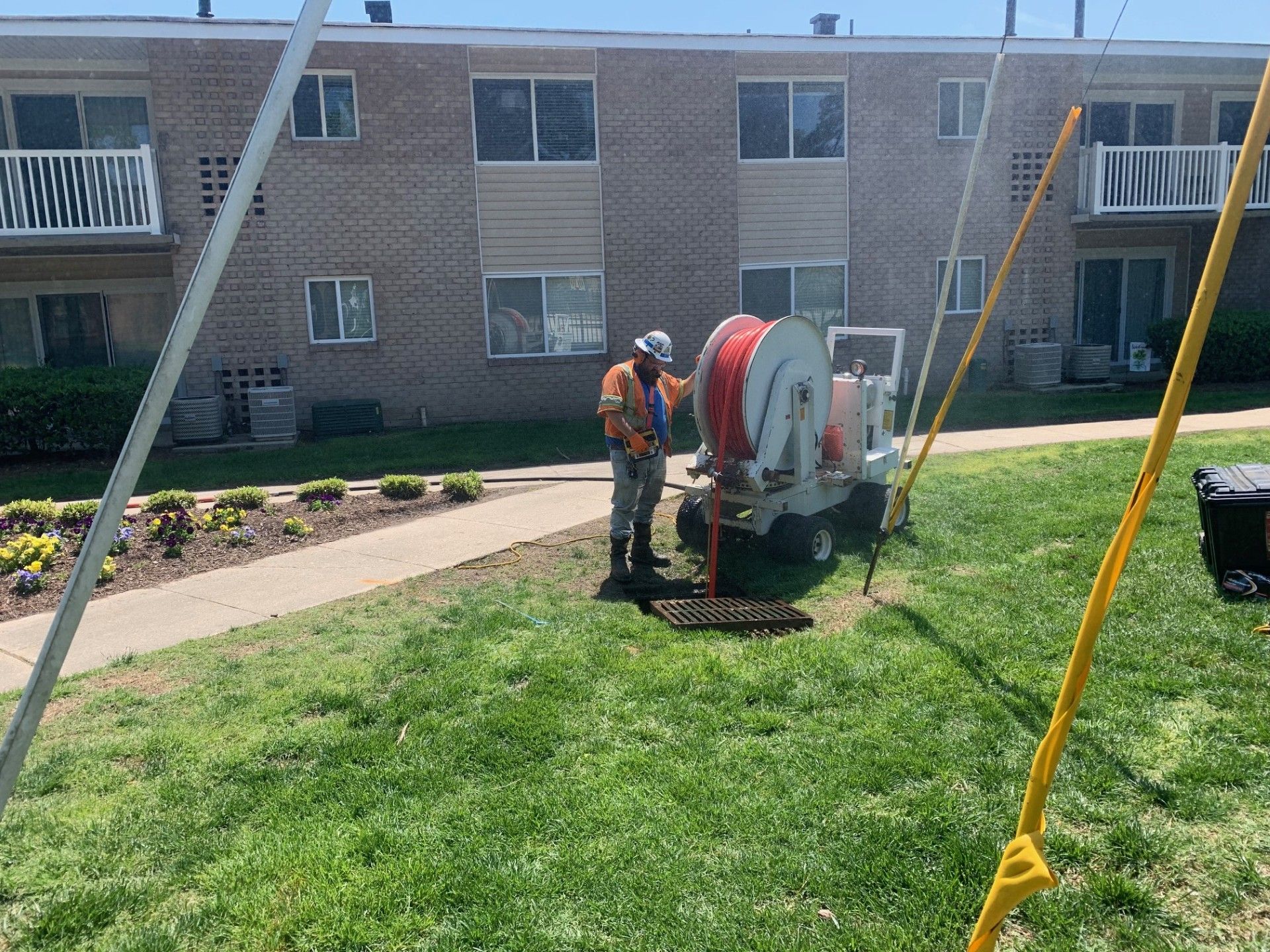 Worker operating a cement mixer on a grassy lawn beside an apartment building