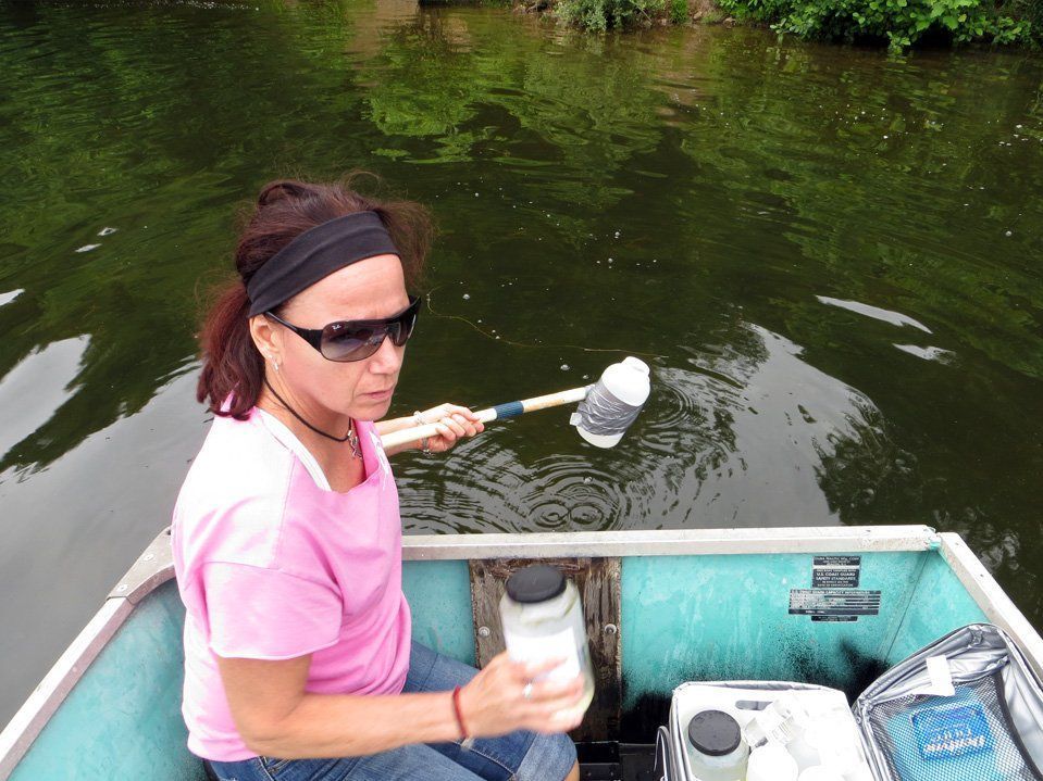 A woman in a pink shirt is sitting in a boat holding a net