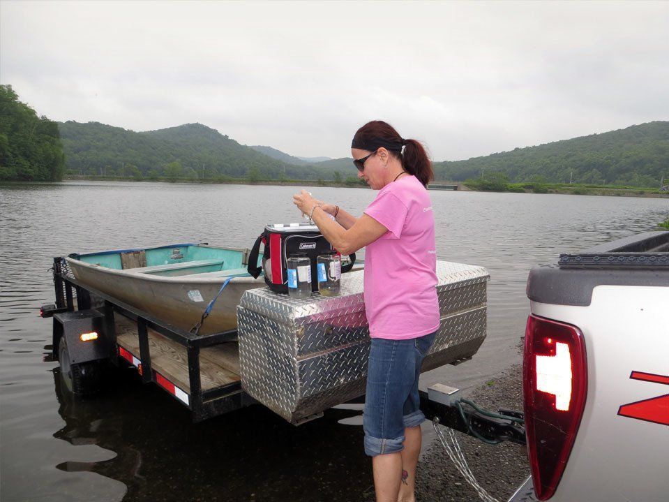 A woman in a pink shirt is standing next to a boat on a trailer